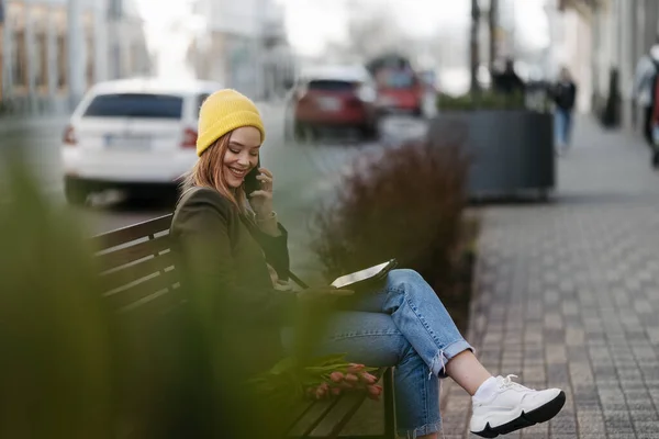 チューリップとデジタルタブレットで街に座っている若い女性 — ストック写真