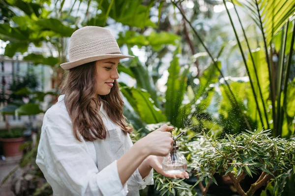 美丽的女园丁在植物园中照料植物的画像 植物学家园艺师用喷雾瓶浇灌植物 — 图库照片