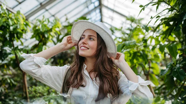 정원에 모자와 배낭을 여성의 온실에서의 식물학 — 스톡 사진