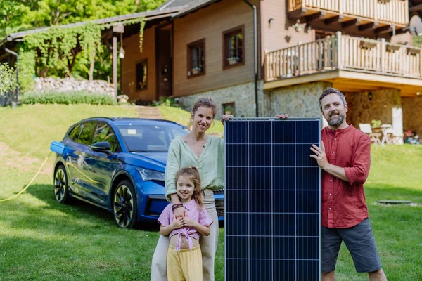 Szczęśliwa Rodzina Pozująca Panelem Fotowoltaicznym Podczas Ładowania Samochodu Elektrycznego — Zdjęcie stockowe