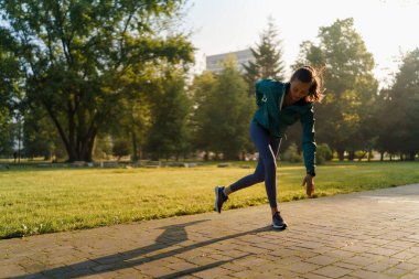 Şehir parkında koşan güzel bir fitness kadınının tam boy portresi. Parkta antrenman. Açık hava idman konsepti.