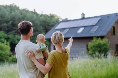 Evlerinin yakınındaki güneş paneli olan aile manzarası. Alternatif enerji, tasarruf kaynakları ve sürdürülebilir yaşam tarzı kavramı.