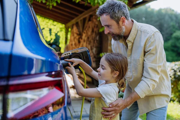 Батько Його Маленька Дочка Заряджають Свій Електричний Автомобіль — стокове фото