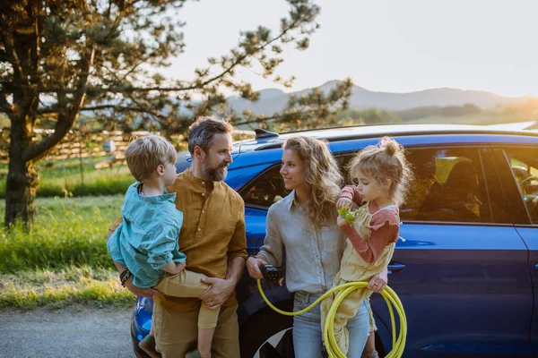 坐在电动车前的快乐家庭 绿色能源的概念和可持续的生活方式 — 图库照片
