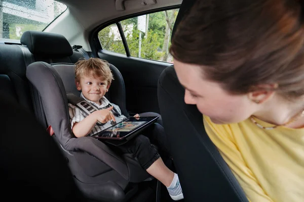 Roztomilý Chlapeček Sedí Autosedačce Hraje Tabletu Matka Kontroluje Svého Syna — Stock fotografie