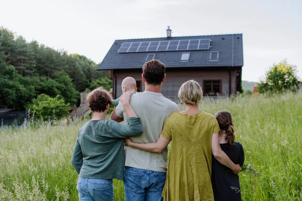 ソーラーパネル付きの家の近くの家族のリアビュー 代替エネルギー 省資源 持続可能なライフスタイルの概念 — ストック写真