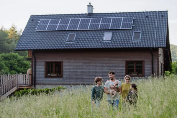 Happy family near their house with a solar panels. Alternative energy, saving resources and sustainable lifestyle concept.