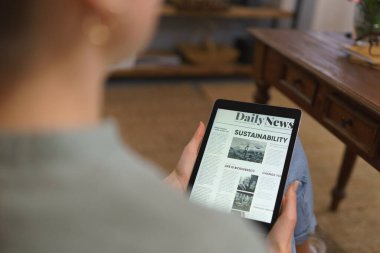 Ekranda haber olan tabletin ayrıntıları. Dijital tablette haber okuyan kadın.
