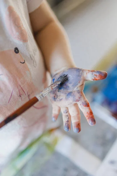 用水彩画用画笔在自己手上画的小女孩的近照 — 图库照片