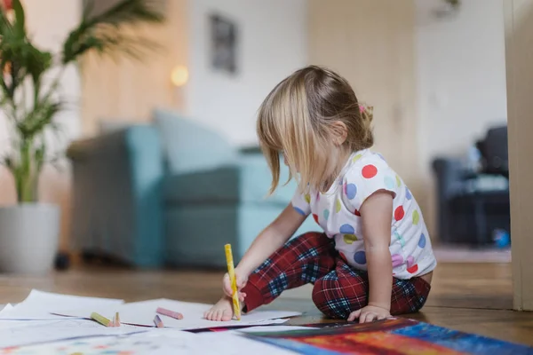 可爱的小女孩用蜡笔画着 坐在客厅的地板上 把自己的脚贴在纸上 — 图库照片