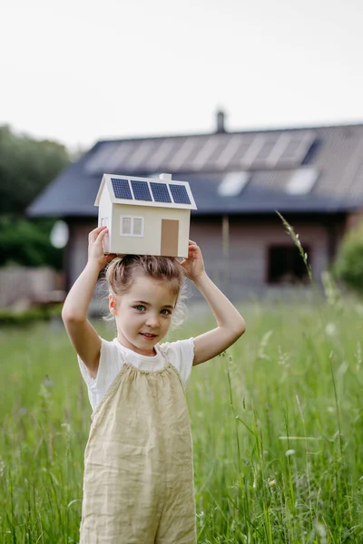 ソーラーパネル付きの家のモデルを保持する少女の肖像 持続可能なライフスタイルと再生可能な資源の概念 — ストック写真