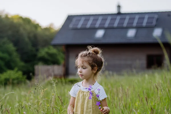 ソーラーパネル付きの家族の家の前に小さな女の子の肖像 持続可能なライフスタイルと再生可能な資源の概念 — ストック写真