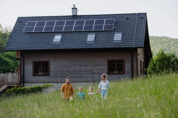 快乐的家庭在屋前 屋顶上挂着太阳能电池板 — 图库照片