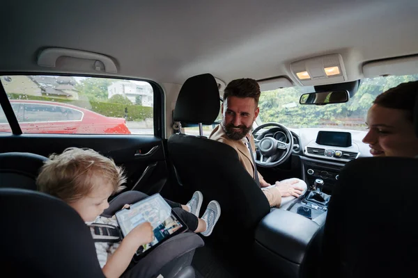 可爱的小男孩坐在他的汽车座位上玩平板电脑 父母在开车前先检查儿子 搭便车安全 — 图库照片