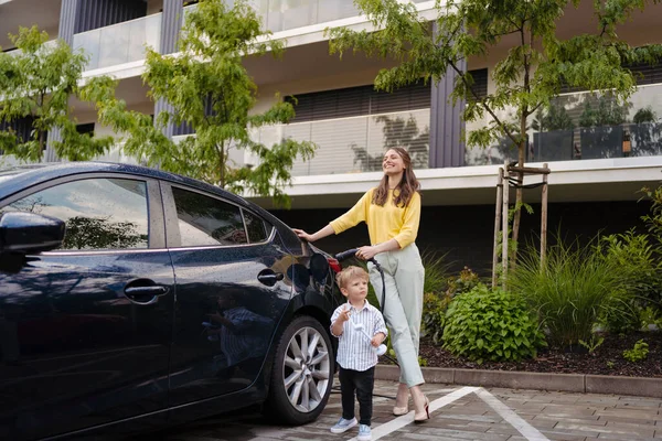 Gülümseyen Anne Küçük Oğlu Sokakta Elektrikli Arabalarını Şarj Ediyorlar Rüzgar — Stok fotoğraf
