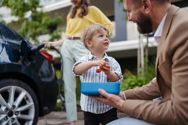 Son Father Having Snack While Mother Unplugging Electric Car Charger — Stock Photo, Image
