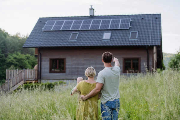 ソーラーパネル付きの家の近くの家族のリアビュー 代替エネルギー 省資源 持続可能なライフスタイルの概念 — ストック写真