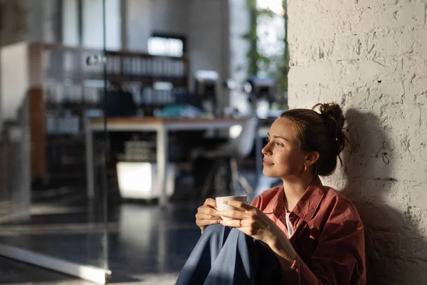 Kendi Ofisinde Kahve Içip Günbatımını Izleyen Mutlu Bir Bayan Girişimci — Stok fotoğraf