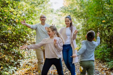 Mutlu aile sonbahar ormanlarında yeşilliklerle eğleniyor..