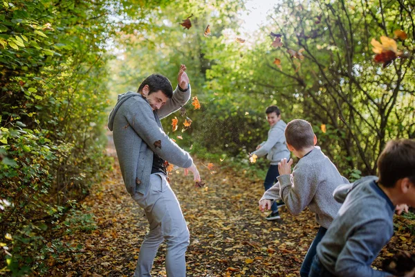 父亲和他的孩子们在森林里玩乐 扔树叶 — 图库照片