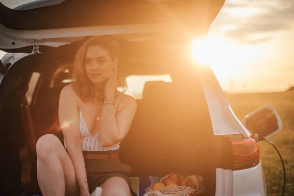 Молодая Женщина Сидящая Багажнике Машины Ждет Зарядить — стоковое фото