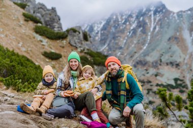 Mutlu aile istirahatı, sonbahar dağlarında yürüyüş yaparken atıştırmalık yemek..