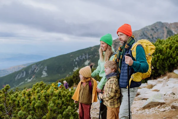 Portrait of happy family hiking together and enjoying the view in autumn mountains.. Hiking with young kids.