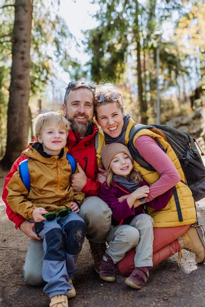 Portrait of happy family hiking together in an autumn mountains. Hiking with young children, on kids friendly trail.