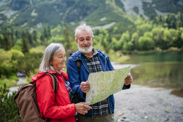 活跃的老夫妇一起在秋天的高山上远足 走在老年人友好的小径上 老夫妇在山里度假庆祝结婚周年纪念日 带背包阅读地图的资深游客 — 图库照片