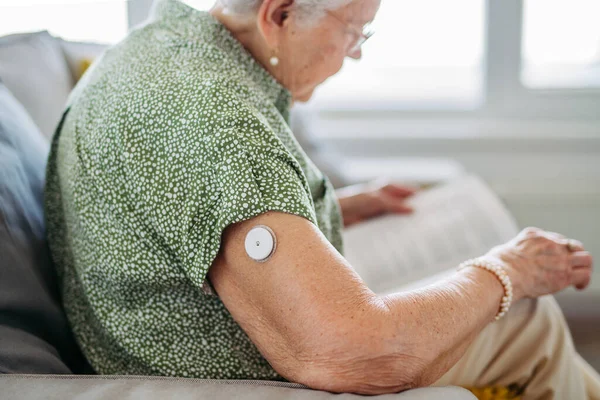糖尿病老年患者使用连续血糖监测器检查家里的血糖水平 Cgm装置使老年妇女的生活更容易 有助于控制她的疾病 并将注意力集中在其他活动上 — 图库照片