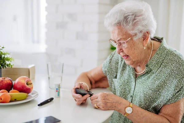 糖尿病老年患者用指尖测血糖仪检查血糖水平 1型糖尿病老年妇女在家中使用血糖监测仪的特征描述 — 图库照片