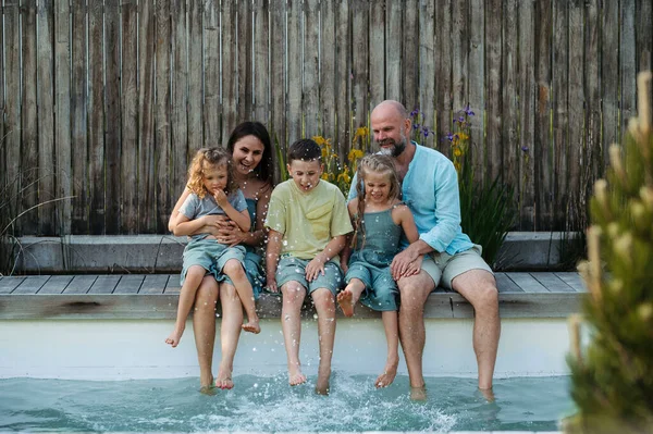 一个快乐的家庭 有三个孩子在一起玩乐 一起坐在游泳池边 家庭联系的概念 — 图库照片