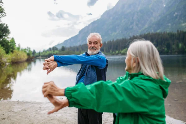 アウトドアヨガをするシニアカップル 太極拳 秋に湖に積み重なります 高齢の夫と妻は山で活発な休暇を過ごし 身体活動の組み合わせを楽しんでいます — ストック写真