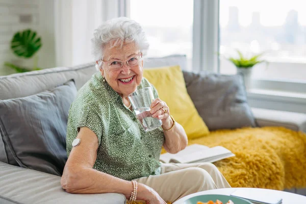 糖尿病老年患者使用连续血糖监测器检查家里的血糖水平 老年妇女喝水以更好地治疗糖尿病 Cgm装置使老年妇女的生活更容易 — 图库照片