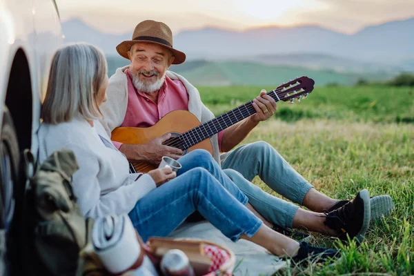 シニアカップルの肖像画は スティーブカーで座って ロングドライブの後にギターを弾く ロシュトリップの高齢者配偶者が背後にあるハイタトラの穏やかな風景を楽しんでいる — ストック写真