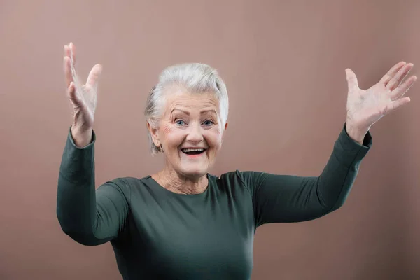 Στούντιο Πορτρέτο Της Χαμογελαστής Ηλικιωμένης Γυναίκας Σηκωμένα Χέρια Κοντά Γκρίζα — Φωτογραφία Αρχείου