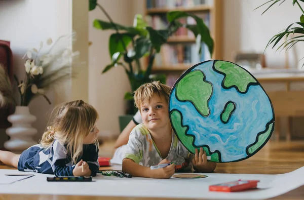 兄弟姐妹们躺在地上 在家里用水彩画 标记和水彩画 创造了一个地球模型 度假期间在家里的一个创意项目 一个准备入学的年轻学生 — 图库照片