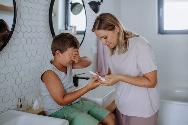 母親は息子の血糖値を家庭でチェックし 指先のブドウ糖メーターを使用しています 糖尿病の少年は 彼の母親が血液サンプルを得るために彼の皮膚をプリックとして見ることができません — ストック写真