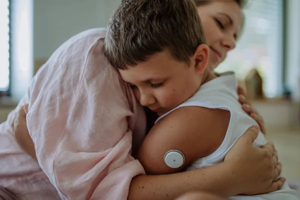 Diabetische Jongen Met Een Continue Glucosemonitor Die Zijn Moeder Omarmt — Stockfoto