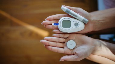 Close up of hands holding diabetes supplies and devices. Continuous glucose monitor, insulin pen, blood glucose meter. Banner with copy space. clipart