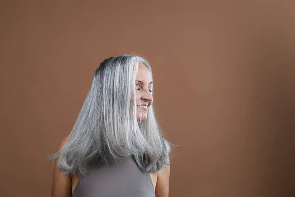 美丽的老年妇女的侧视图 长长的浓密的白发 在棕色粉红的背景上分离 复制空间 — 图库照片