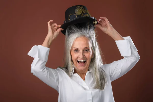 彼女の頭に帽子をかけるシャツで幸せなシニアの女性の肖像画 スタジオ撮影 — ストック写真