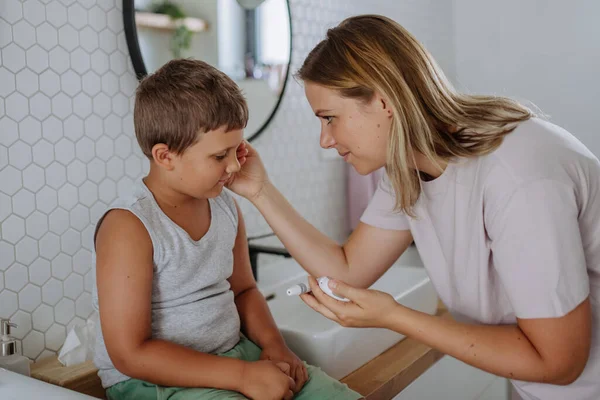 母親は息子の血糖値を家庭でチェックし 指先のブドウ糖メーターを使用しています 糖尿病の少年は血液検査の結果を待っている 彼女の — ストック写真