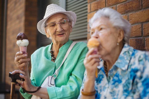 城市里两个高级女性朋友的画像 在炎热的夏天吃着冰激凌 上了年纪的女士在城里度暑假 参加团体旅行的退休人员 高级休假和旅行的概念 — 图库照片