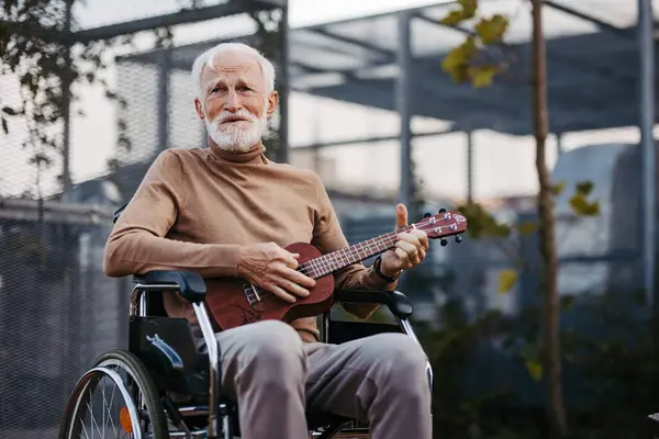 Starszy Mężczyzna Siedzący Wózku Inwalidzkim Zewnątrz Grający Ukulele Emerytowany Muzyk — Zdjęcie stockowe