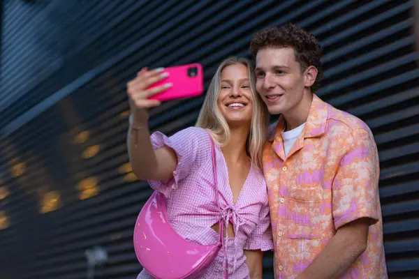 Gen Z couple in pink outfit taking selfie before going the cinema to watch movie. The young zoomer girl and boy watched a movie addressing the topic of women, her position in the world, and body image