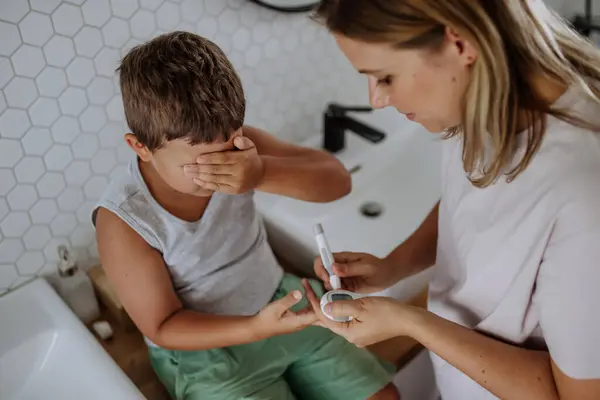 母親は息子の血糖値を家庭でチェックし 指先のブドウ糖メーターを使用しています 糖尿病の少年は血液検査の結果を待っている 彼女の — ストック写真