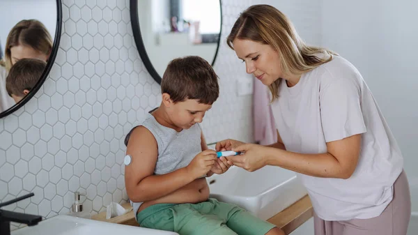 彼の腹部にインスリンを注射する糖尿病の少年の母親 浴室で注射針で絶縁する1型糖尿病の少年 — ストック写真