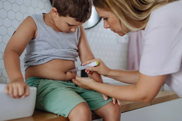 糖尿病男孩的母亲在他的腹部注射胰岛素 在浴室用注射器针隔离1型糖尿病的小男孩 — 图库照片