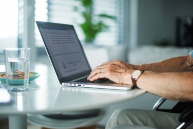 Laptop klavyesine yazı yazan yaşlı bir adamın yakın çekim görüntüleri. Evden çalışma kavramı.